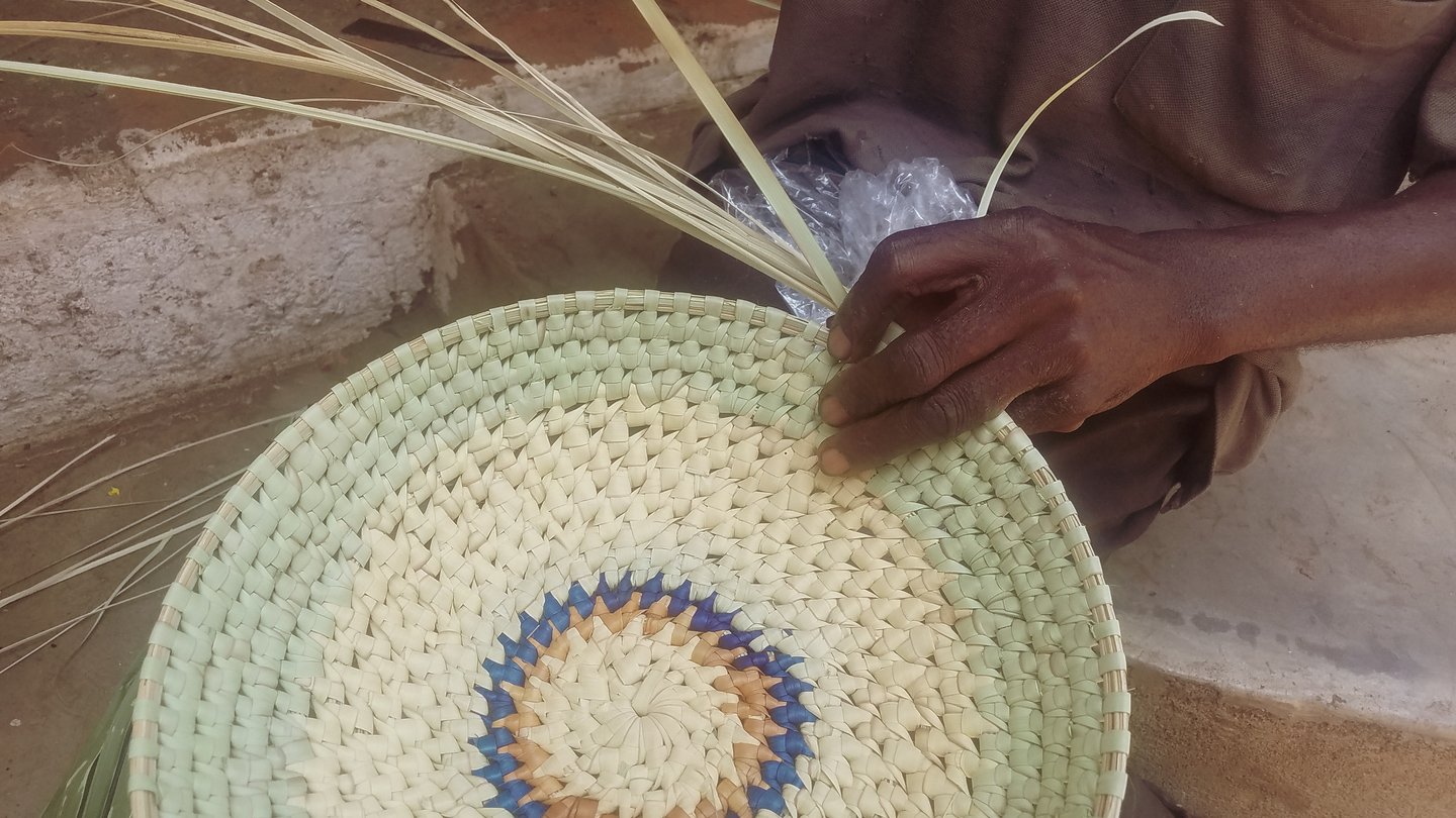 Weaving a basket out of palm fronds in Zambia