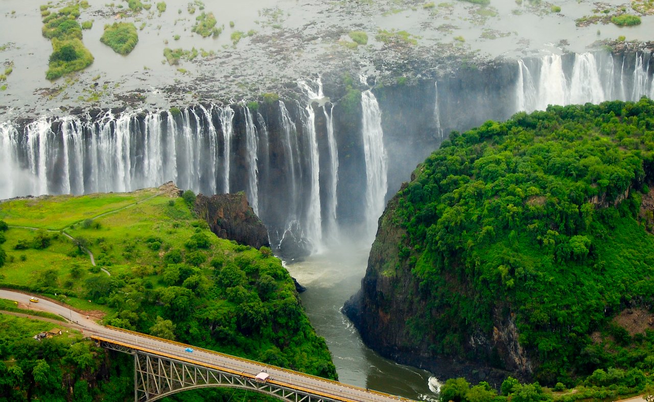 An aerial view of the immense Victoria Falls with a bridge in the foreground