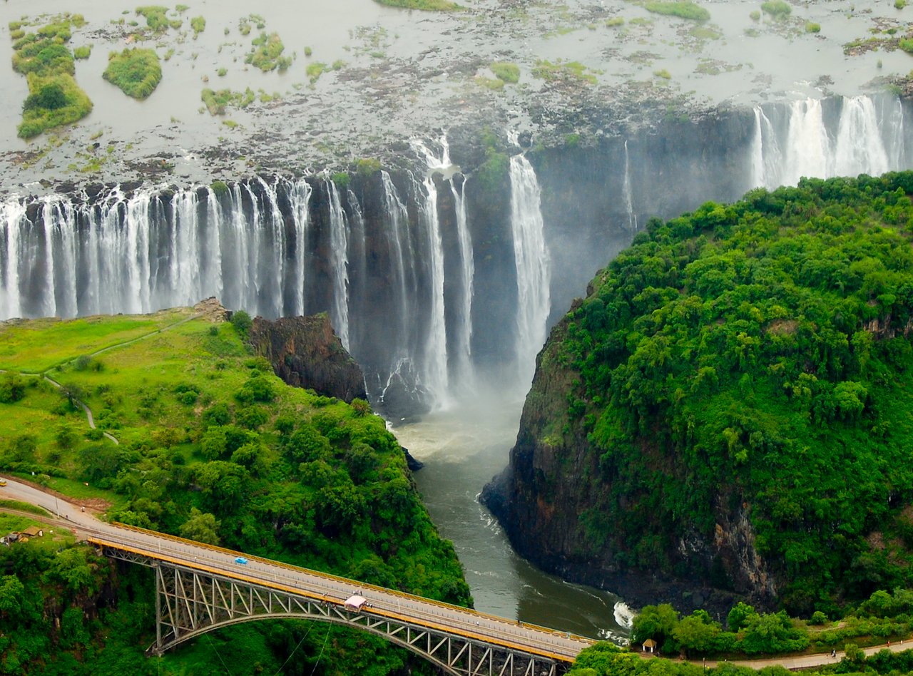 An aerial view of the immense Victoria Falls with a bridge in the foreground