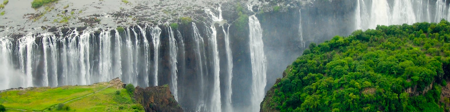 An aerial view of the immense Victoria Falls with a bridge in the foreground