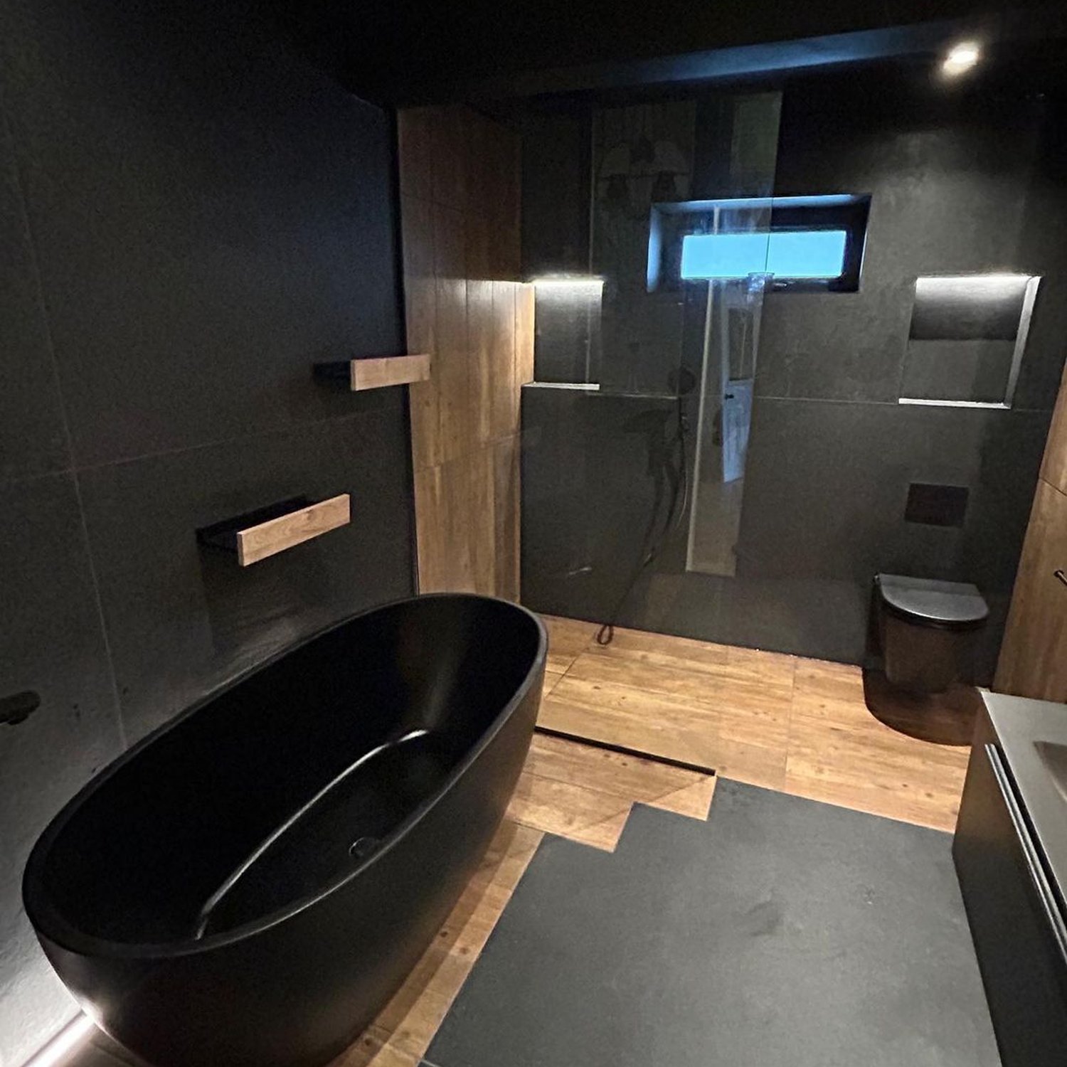 A modern bathroom with dark tones and contrasting textures