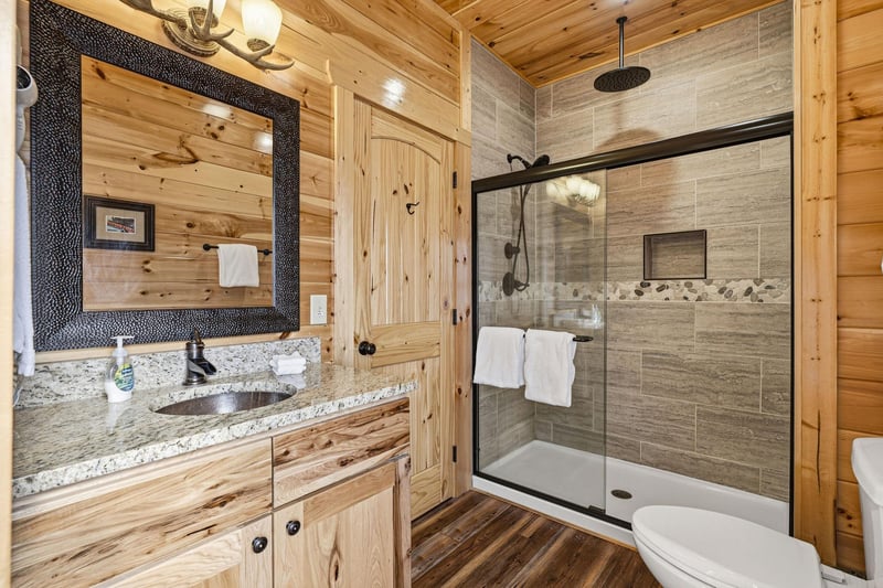 Step into your private spalike bathroom featuring a luxurious stonetiled shower and rustic wood accents for the perfect mountain retreat experience.