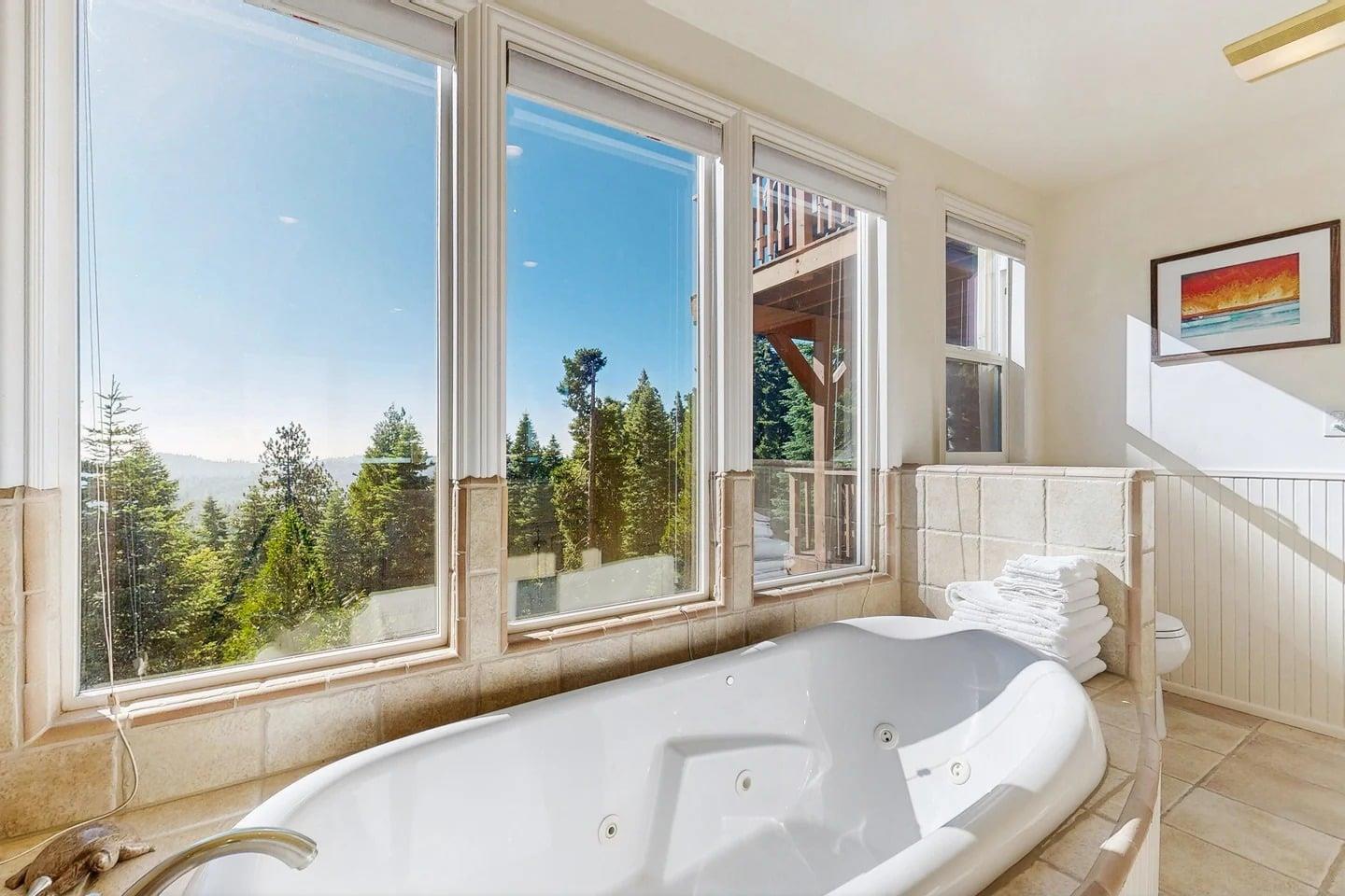 Ensuite bathroom equipped with a standalone jet tub, stand alone shower, dual vanity sink, and plenty of natural lighting.