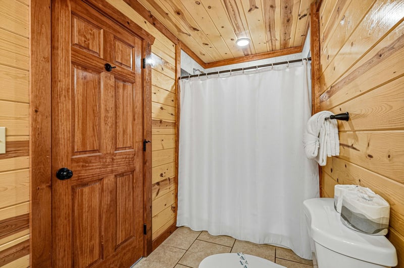 Step into your rustic bathroom where warm wood walls create a cozy cabin atmosphere, complete with fresh towels and everything you need to refresh.