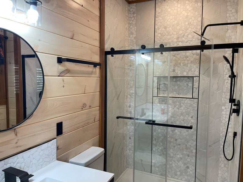 Luxurious bathroom with modern glass shower, elegant marble tiles, and warm wood accents creating your perfect spa retreat.