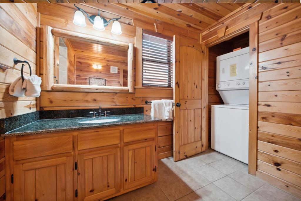 Rustic log cabin bathroom with granite vanity, stacked washerdryer, and charming wood details throughout your mountain retreat.
