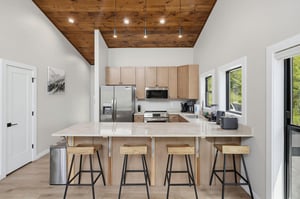 Gather around the spacious kitchen island and enjoy your morning coffee beneath the stunning woodplank ceiling. Modern appliances and natural light create a warm, inviting space for cooking and conve