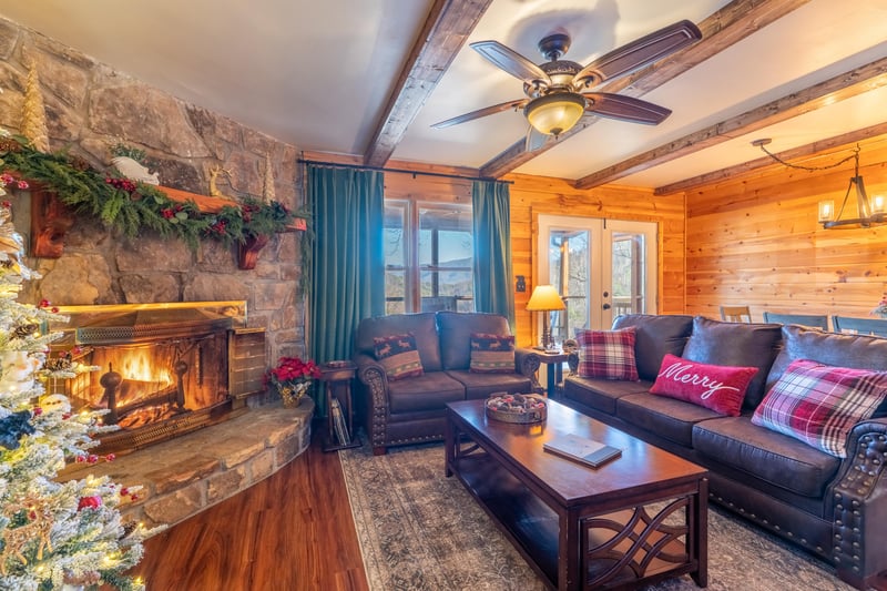 Sink into plush seating beside a crackling stone fireplace, where rustic wood beams and festive touches create your perfect mountain escape.