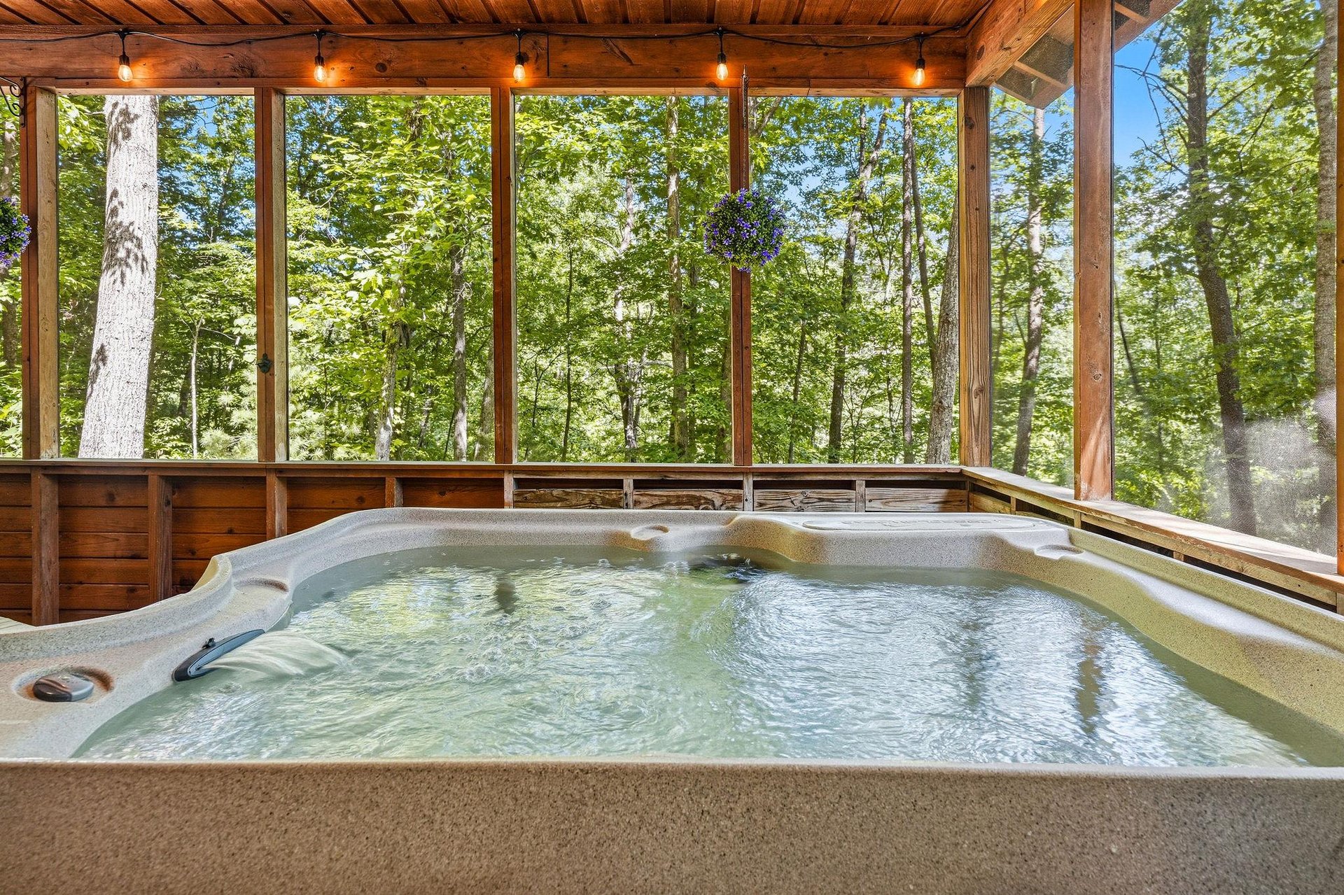 Soak in your private hot tub surrounded by floortoceiling forest views, where warm waters and rustling leaves create your perfect retreat beneath a timber ceiling with soft ambient lighting.