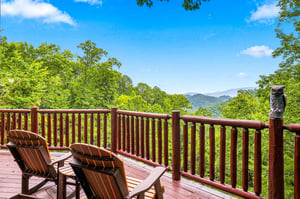 Mountain peaks rise beyond lush green forest canopy from this peaceful private deck retreat with rustic charm.