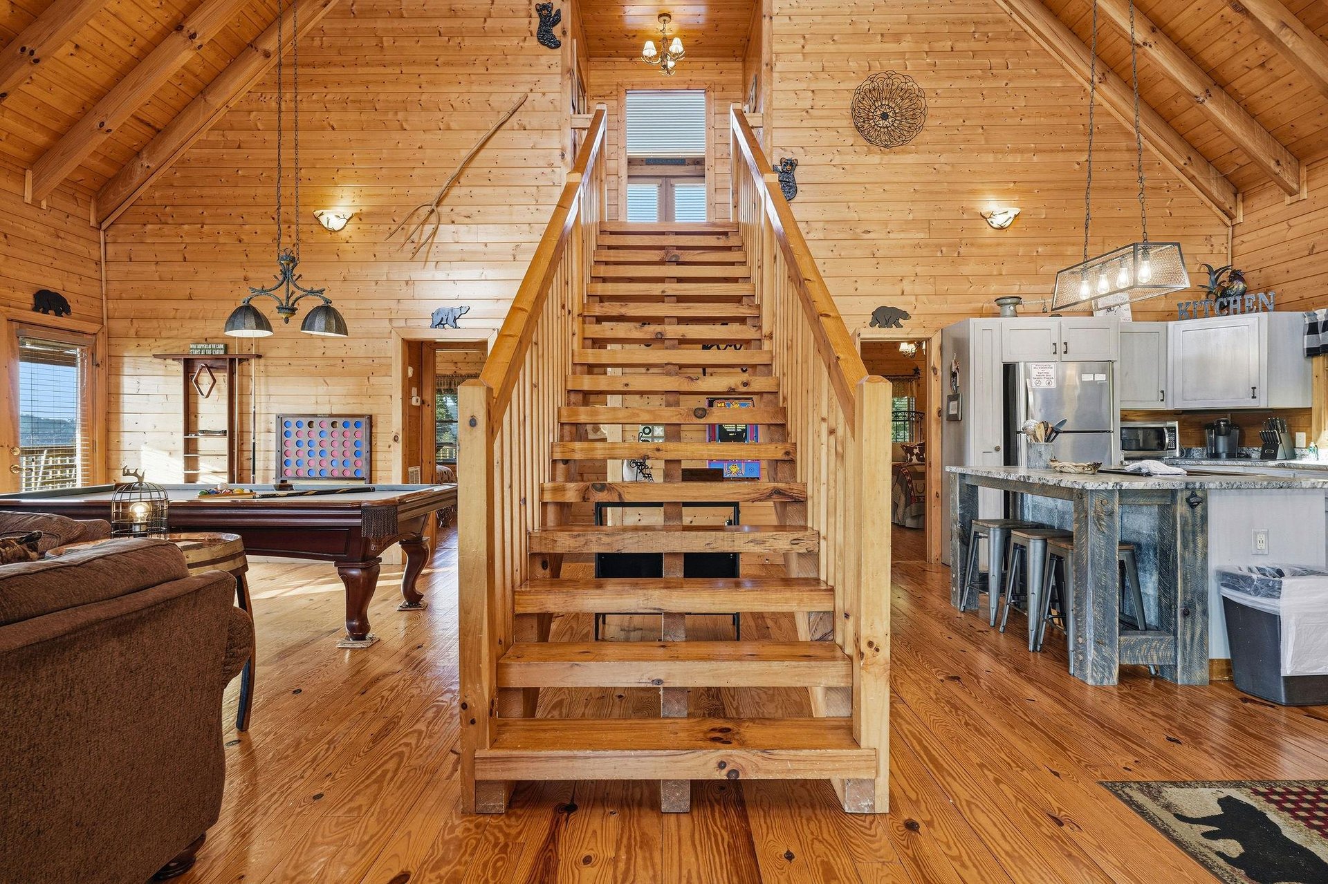 Soak in the warm glow of natural wood and soaring cathedral ceilings. Your openconcept retreat blends game room fun, a welcoming kitchen, and cozy seating under rustic charm and handcrafted details.