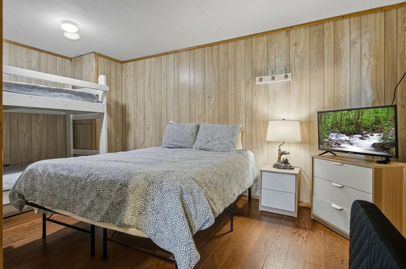 Your cozy bedroom features warm wood paneling, comfortable beds, and entertainment for relaxing after your adventures.