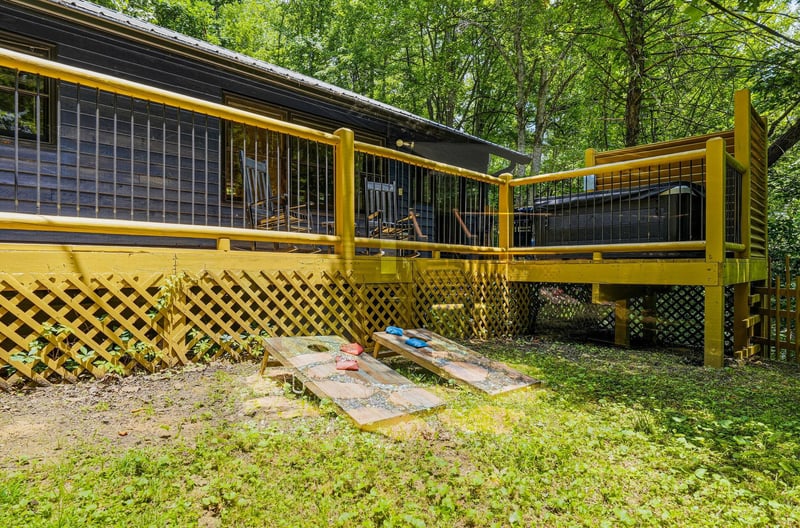 Your private retreat features a cheerful yellow deck nestled in lush forest surroundings, with lattice details and a shaded seating area perfect for morning coffee or evening relaxation.