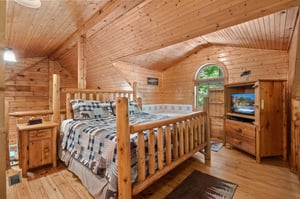 king log bed with TV, dresser, natural lighting and jacuzzi tub next to the bed