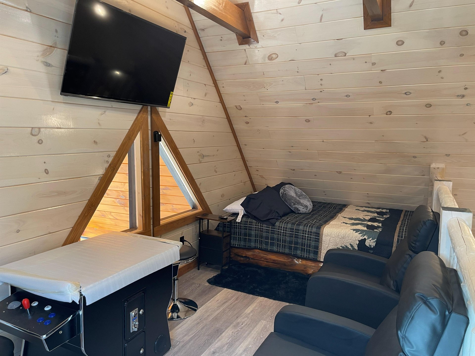Cozy up in your rustic loft retreat with warm wood walls, comfy seating, and modern entertainment for perfect relaxation.