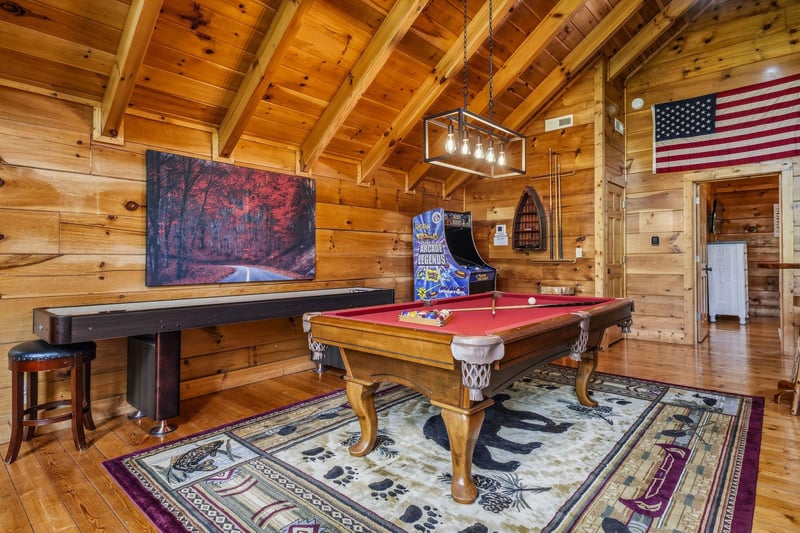 Challenge your friends to a friendly game of pool in this rustic woodpaneled game room, complete with an arcade and classic cabin charm.
