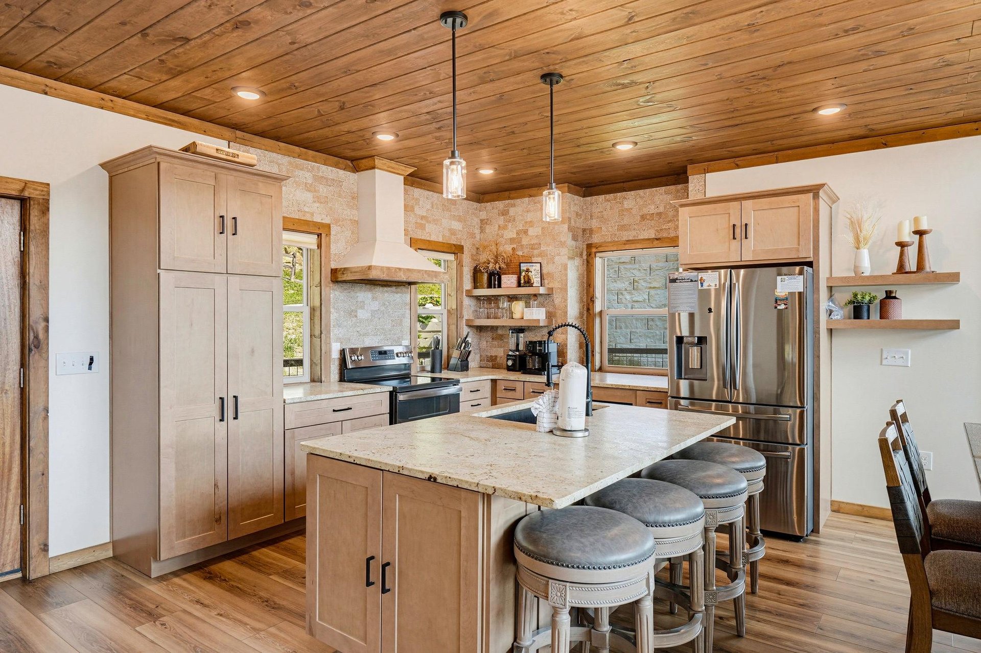 Gather around the spacious island in this warm, woodaccented kitchen where stainless steel appliances and thoughtful design make cooking feel effortless and inviting.