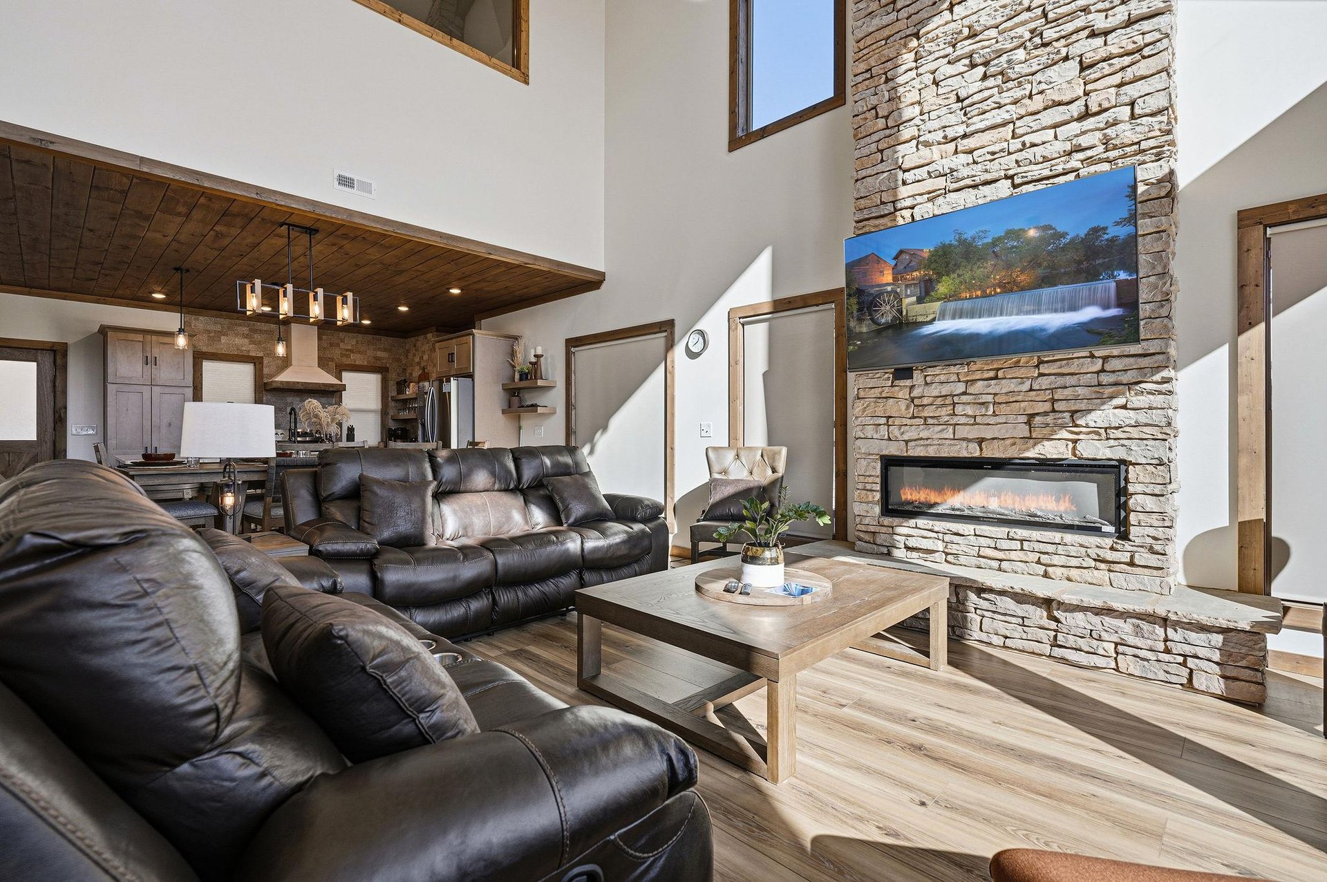Cozy up in your spacious living room where leather recliners face a warm stone fireplace and smart TV for perfect evening relaxation.