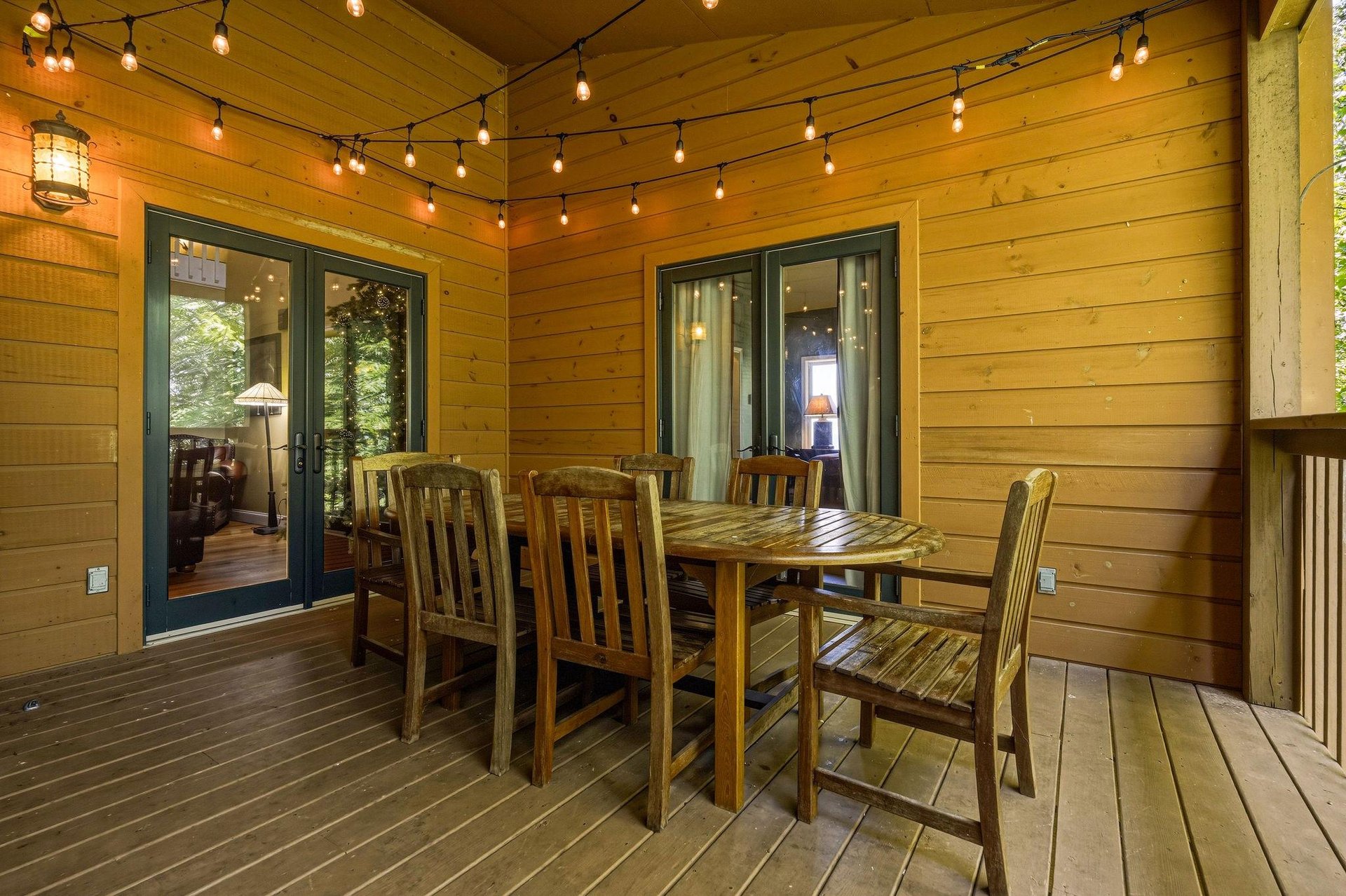 Gather around this charming outdoor dining space, where warm string lights and natural wood create the perfect setting for memorable meals under the covered deck.