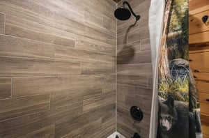 Step into your private shower with woodlook tile, sleek fixtures, and a rainfall showerhead that makes every rinse feel rejuvenating.