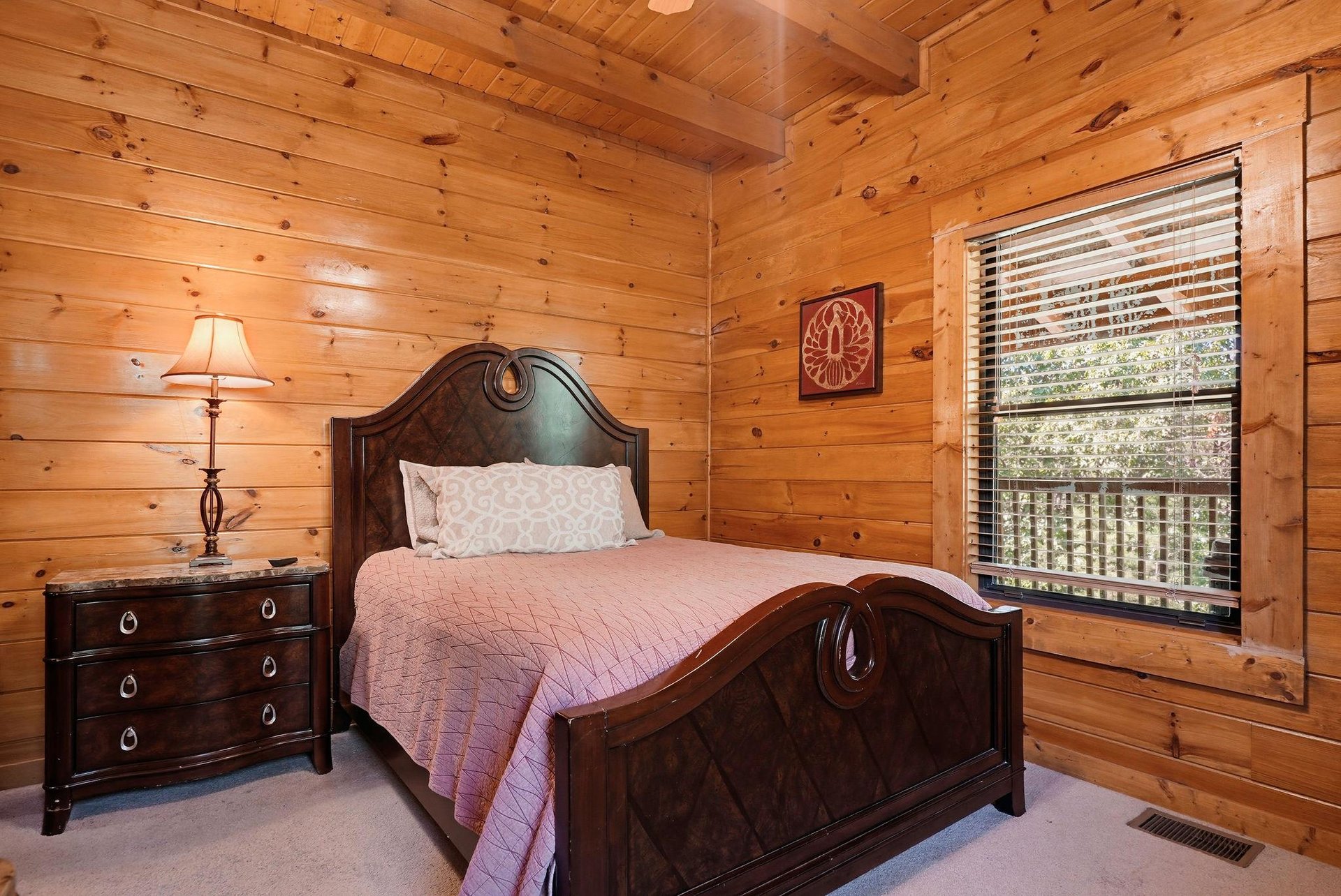 Drift off in this cozy cabin bedroom wrapped in warm wood and natural light. The elegant bed and peaceful forest views through your window promise restful mountain mornings.