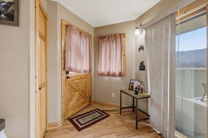 Step into your charming entryway with rustic wood accents and cozy plaid curtains welcoming you home.