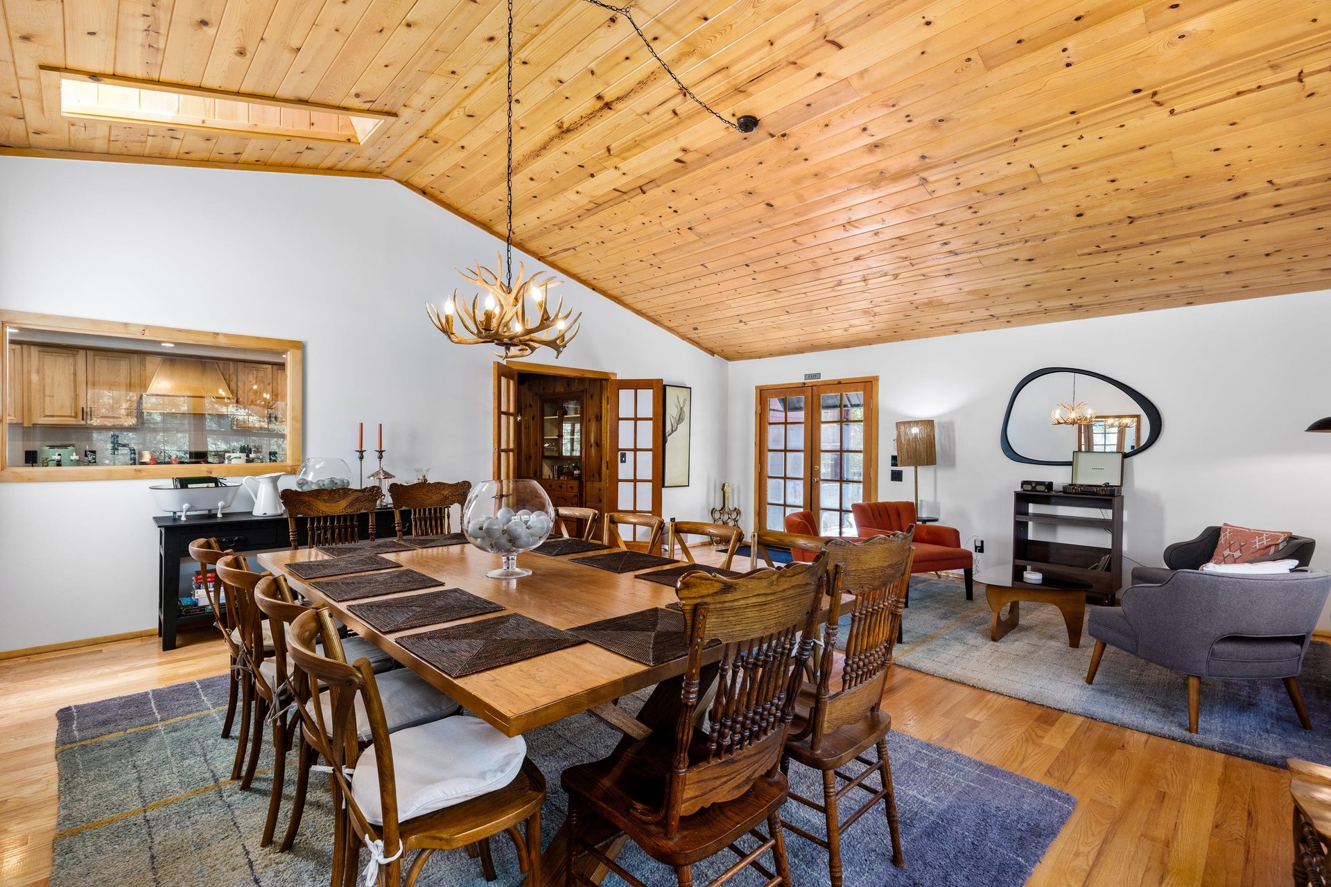 Gorgeous dining room with a large dining table under an antler chandelier. Sitting area next to dining space.