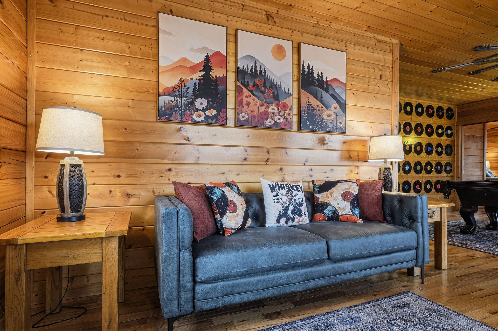 Sink into the plush leather sofa surrounded by warm wood walls and mountain art, creating your perfect retreat for relaxation.