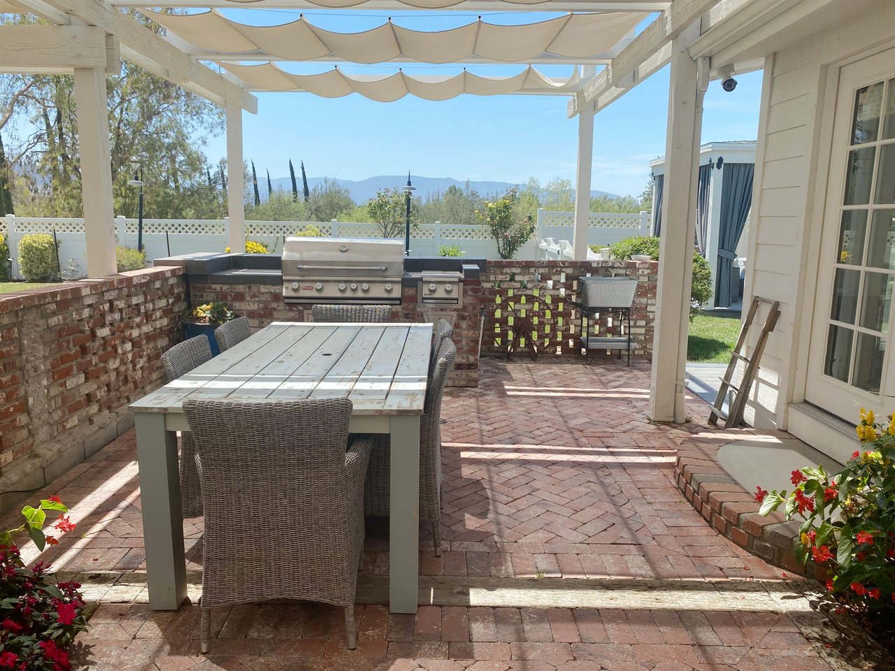 Follow the garden path to French doors and an inviting outdoor dining area with a BBQ grill.