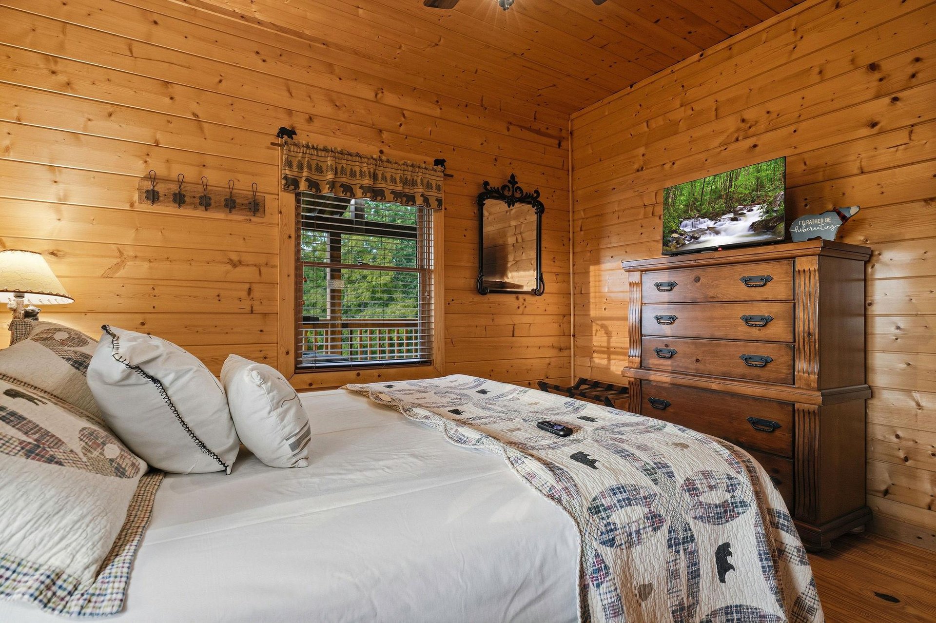 Sink into soft linens in your cozy cabin bedroom, where warm wood walls and rustic touches create the perfect mountain retreat for restful nights.