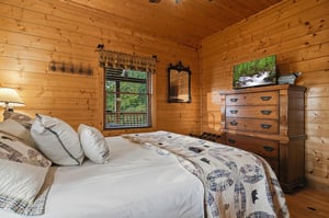 Sink into soft linens in your cozy cabin bedroom, where warm wood walls and rustic touches create the perfect mountain retreat for restful nights.