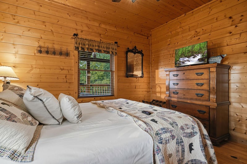 Sink into soft linens in your cozy cabin bedroom, where warm wood walls and rustic touches create the perfect mountain retreat for restful nights.