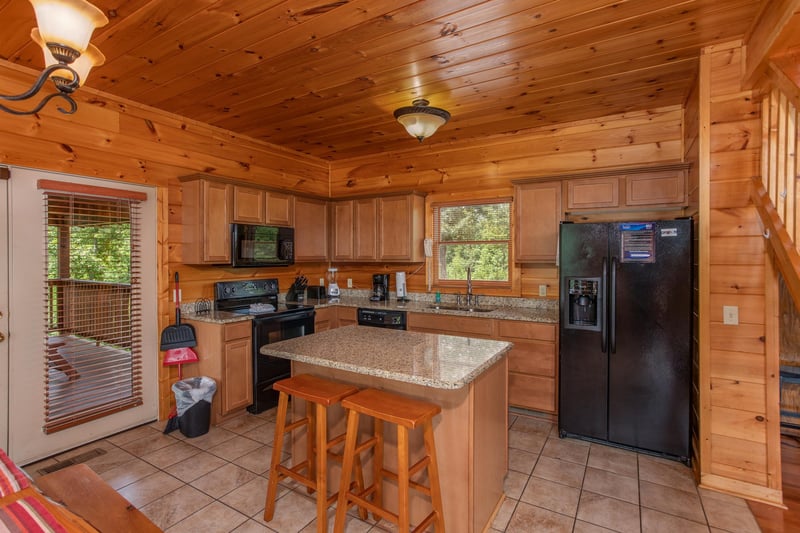 Kitchen with black appliances and an island and seating for two at Four Seasons Lodge, a 3bedroom cabin rental located in Pigeon Forge