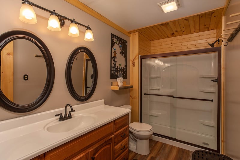 Single vanity sink with 2 round mirrors and walk in shower
