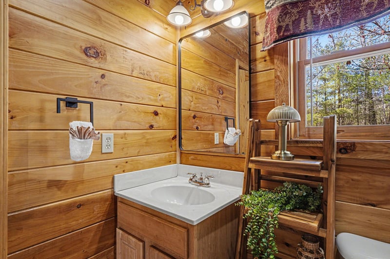 Step into your rustic bathroom featuring warm wood walls, modern fixtures, and a forest view that makes every moment feel like a mountain retreat.