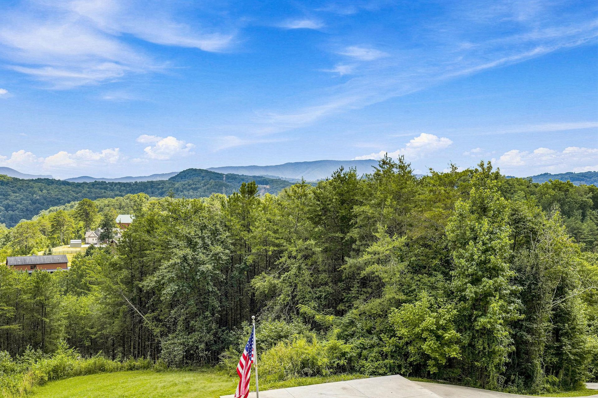 Expansive mountain vistas stretch across lush green valleys, offering sweeping views of layered ridges beneath vibrant blue skies and scattered clouds.