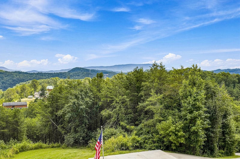 Expansive mountain vistas stretch across lush green valleys, offering sweeping views of layered ridges beneath vibrant blue skies and scattered clouds.