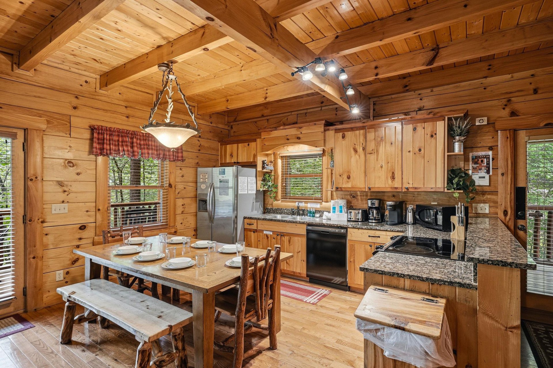 Gather around the rustic wooden table in your fully equipped cabin kitchen, where warm pine walls and modern appliances blend seamlessly for memorable meals together.