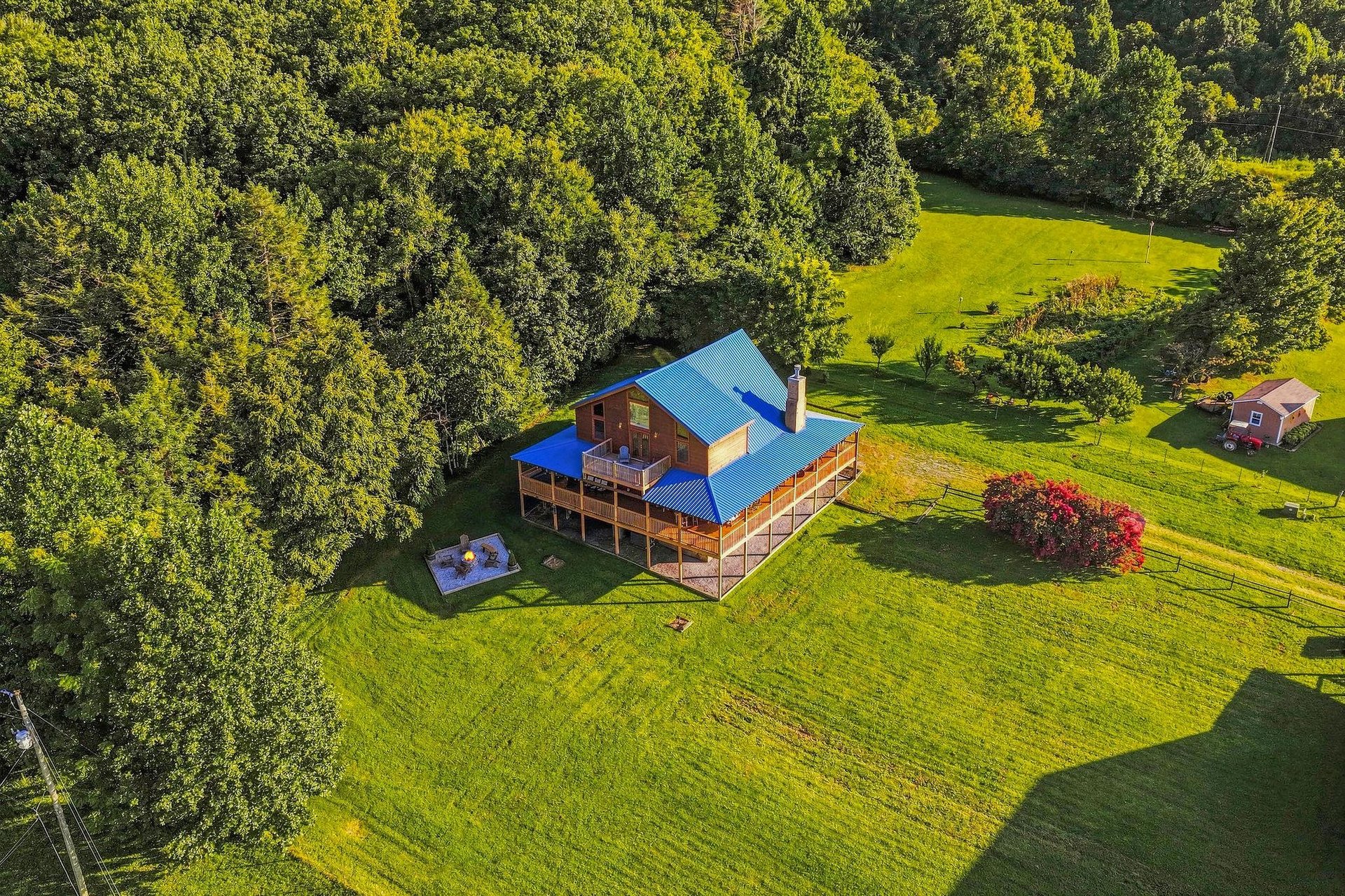 Aerial view captures the vacation rental surrounded by lush green lawn and mature trees, with an outbuilding nestled nearby for added storage or amenities.