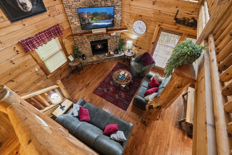 Gather around the warmth of the stone fireplace in your spacious living room, where rustic log walls and cozy seating create the perfect mountain retreat for relaxing evenings together.