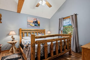 Step into your cozy retreat with a handcrafted log bed beneath soaring vaulted ceilings, where rustic charm meets peaceful mountain comfort.