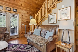 Sink into this cozy leather loveseat in your rustic cabin retreat. Natural wood surrounds you from floor to ceiling, while warm lamps set the perfect mood for unwinding after exploring outdoors.