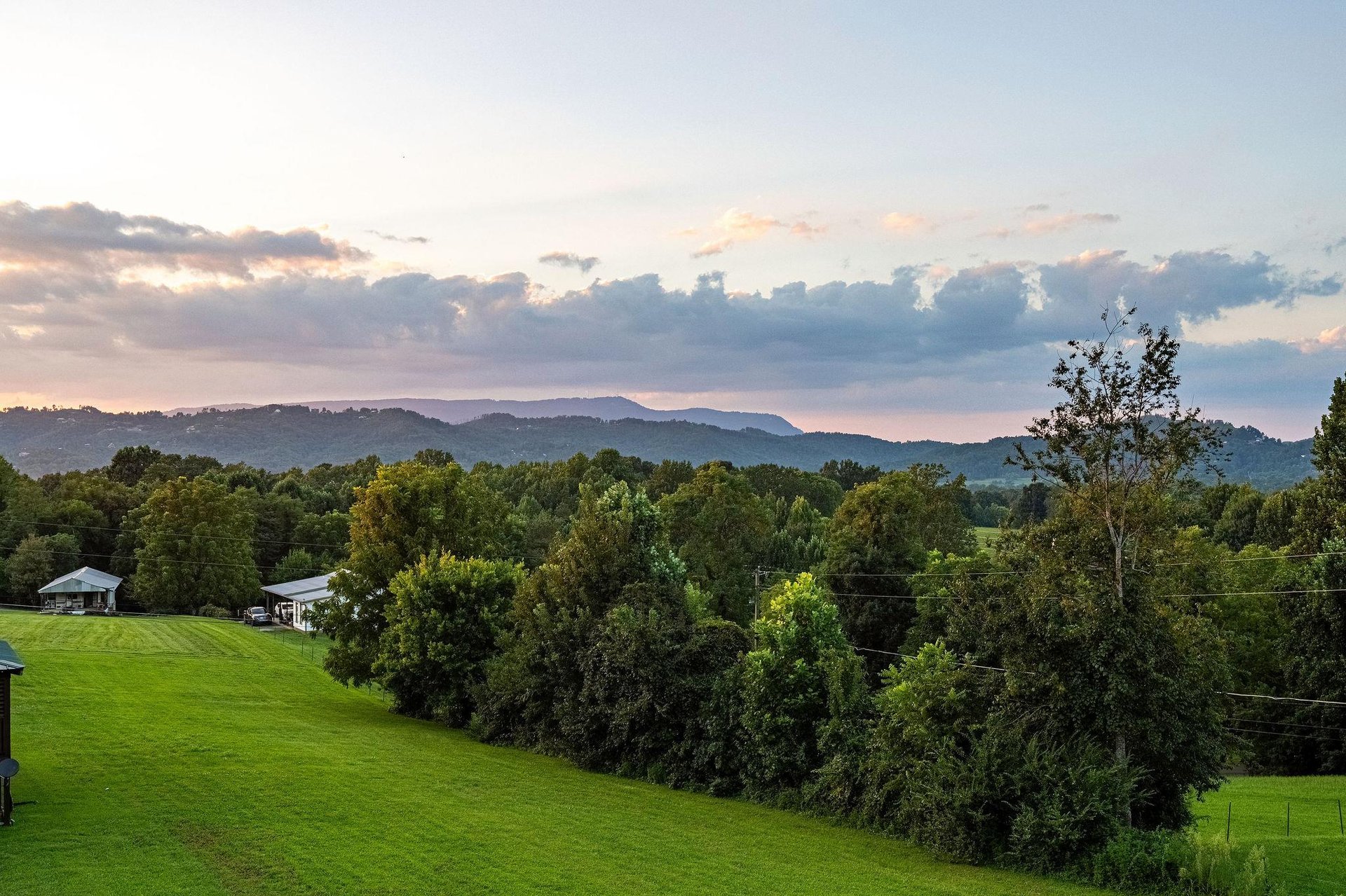 This property sits in a tranquil mountain setting with layered ridges and lush green surroundings, offering a peaceful rural escape as evening light softens the sky.