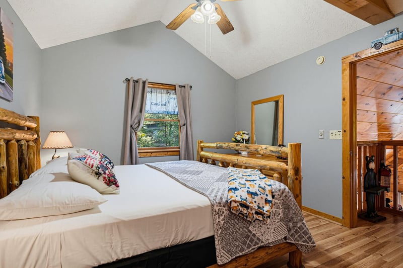 Your cozy mountain retreat features vaulted ceilings with a natural wood beam, rustic log furniture, and soft natural light. Relax in your peaceful bedroom after a day of adventure.