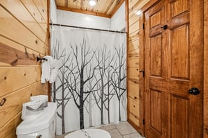 Step into your private rustic bathroom where warm wood meets modern comfort, complete with artistic shower curtain and fresh towels.