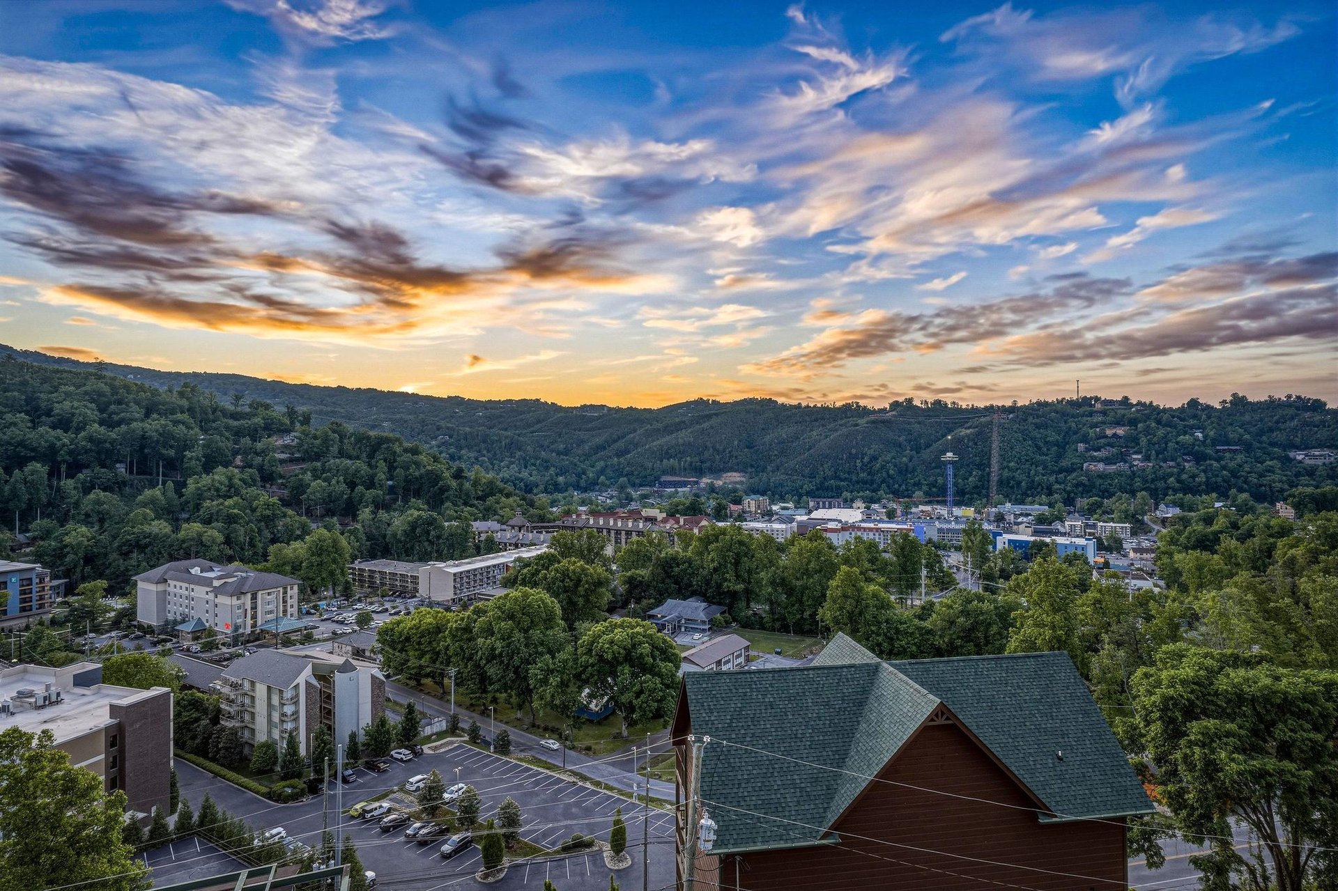 Aerial view capturing the surrounding town nestled among forested hills at sunset, showcasing the propertys scenic location in a vibrant mountain community.