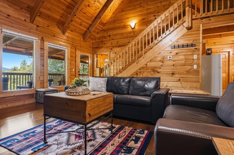 Unwind in your cozy cabin retreat with soaring ceilings, rustic wood details, and leather seating. Large windows frame mountain views while the lofted space adds charm to your getaway.