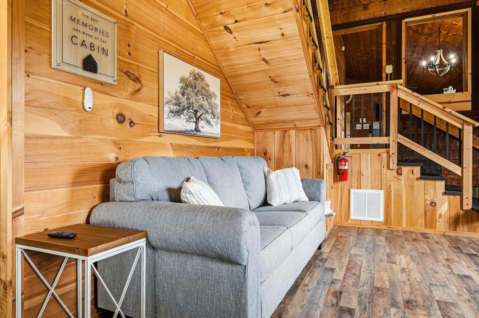 Sink into the plush sofa in your cozy cabin retreat, where warm wood surrounds you and a lofted bedroom awaits above. Everything you need for a peaceful getaway is right here.
