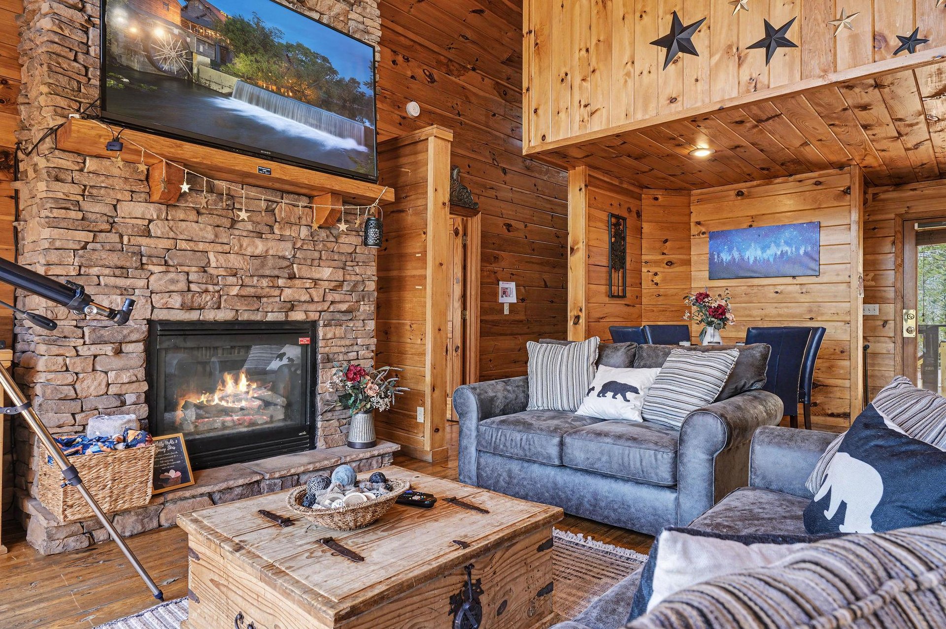 Cozy up by your crackling stone fireplace in this rustic living room, where warm wood surrounds you and starlight details add charm overhead.