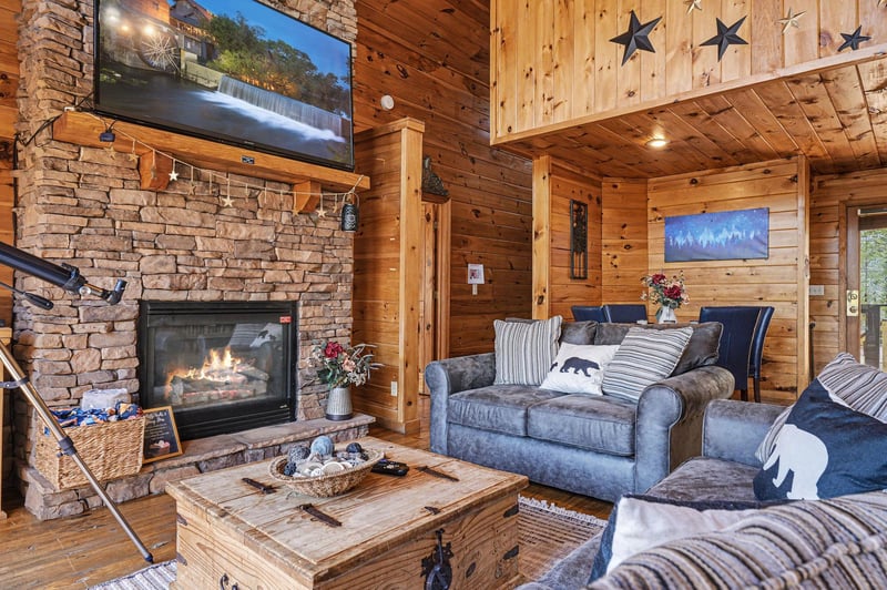 Cozy up by your crackling stone fireplace in this rustic living room, where warm wood surrounds you and starlight details add charm overhead.